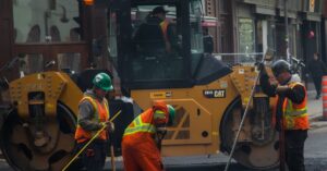 Workers and machinery paving a road in urban Québec City, Canada.